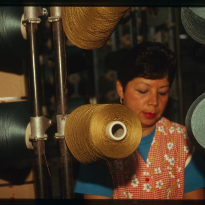 "Woman with spools of thread in warping department," photograph by Martha Cooper, 1994.