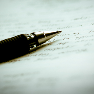 Stock image of pen resting on notebook filled with writing